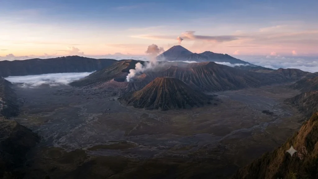 Yogyakarta to Bromo volcanic caldera at dawn with smoking cone and pink sunrise light over Java